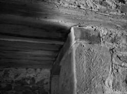 PA͎OV: povalov strop z devnch hrannch trm nad chodbikou v zpadn zdi a kamenn ostn s devnm pekladem portlu vedoucho ke schoditi v tlouce zdi. Na stnch mstnosti z rulovch desek jsou viditeln podezvan spry. V pozad se nachz zazdvka romnskho portlu (foto M. Falta 2010).